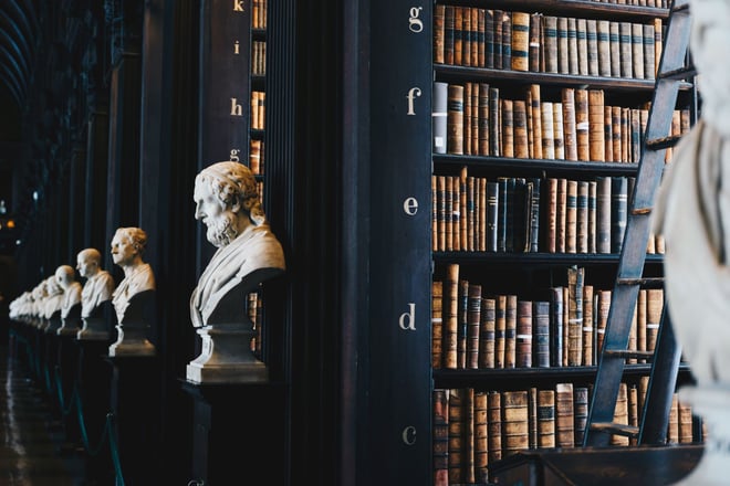 A library with white marble busts of historic men